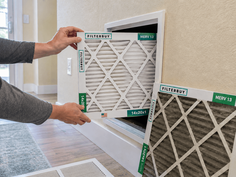 Homeowner replacing a dirty HVAC filter with a new Filterbuy MERV 13 filter during a smoke event.