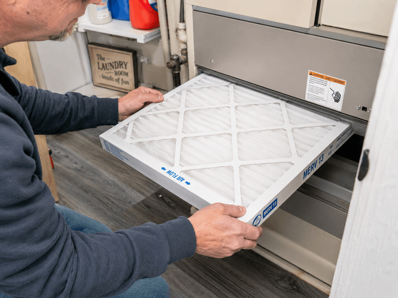 Homeowner installing a MERV 13 air filter to protect indoor air during a wildfire smoke event.